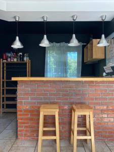 a bar with two wooden stools at a brick wall at Pensiunea Sandra in Bran