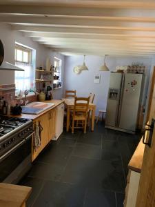 een keuken met een koelkast met vriesvak en een tafel bij Forsythia cottage with surf and cycle hire in Wrafton