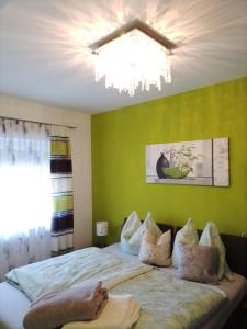 um quarto com uma cama com paredes verdes e um lustre em Ferienwohnung Krenn em Feldbach