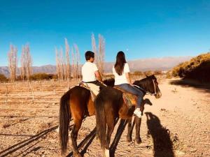 dos personas montando a caballo en un camino de tierra en Estancia Rio de Arena 
