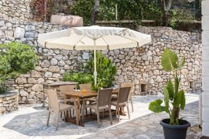 une table et des chaises avec un parasol sur une terrasse dans l'établissement Seaview Villa Leana with Private Pool by Konnect, Nisaki, à Nisakion