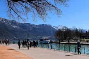 a group of people walking on a sidewalk next to a boat at LE LOFT SOMMEILLER 19*** Près du Lac in Annecy