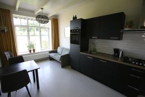 a kitchen with black cabinets and a living room at Recreatieappartement BoerdeRijlst - De Kamer in Sint Nicolaasga +18 photos