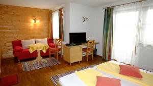 una camera con 2 letti, un divano rosso e una scrivania di Landhaus Franzelin a Längenfeld
