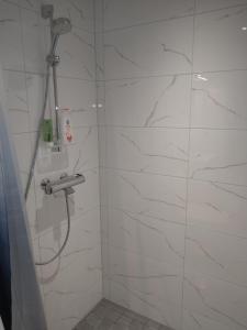 a bathroom with a shower with white marble walls at Apartment Songhill in Kuopio +14 photos