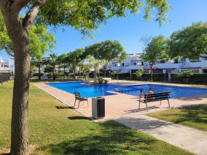 two people sitting on a park bench near a swimming pool at JARDIN 8 JOZMAR in Alhama de Murcia