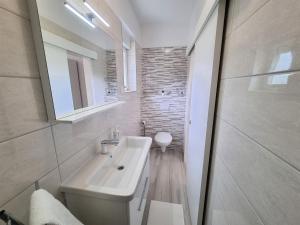 a white bathroom with a sink and a toilet at Apartment House Kastelan in Banjol