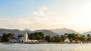 a town on the water with mountains in the background at Pousada Refúgio Ouro Fino - Flats & Suítes in Paraty