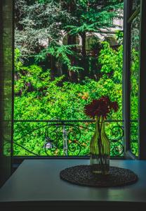 un vase avec des fleurs sur une table devant une fenêtre dans l'établissement LibertySuite Qcview2, à San Pellegrino Terme