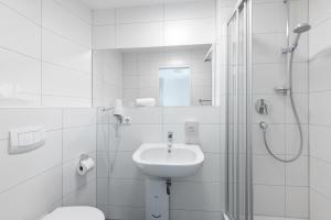uma casa de banho branca com um lavatório e um chuveiro em Hotel Garni am Olgaeck em Stuttgart