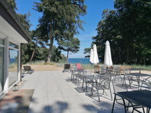 un patio con mesas, sillas y sombrillas blancas en Strandhotel Lindequist, en Ostseebad Sellin