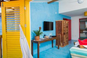 Habitación con cama, escritorio y TV. en Pousada Rosa dos Ventos, en Praia do Forte