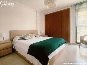 um quarto com uma cama grande e um cobertor verde em Apartment Sabbia by Gabbeach Valencia em Valência