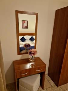 a dressing table with a mirror and flowers on it at HC Apartments Kaliakria in Topola