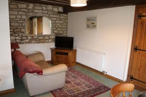 a living room with a couch and a tv at Flat 1 - The Old Mill - Bowbridge Lock - Stroud in Stroud