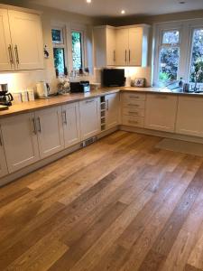 a kitchen with white cabinets and wooden floors at Cotswolds Luxury House in Central Bourton Large Sleeps 2-11. Pet Friendly. in Bourton on the Water