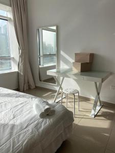 a bedroom with a bed and a table and a window at skynest homes studio in JLT in Dubai