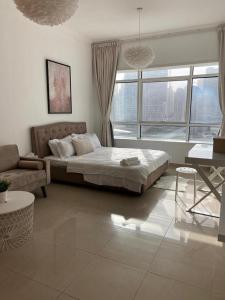 a bedroom with a bed and a couch and a window at skynest homes studio in JLT in Dubai