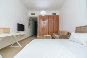 a white bedroom with a bed and a desk at skynest homes studio in JLT in Dubai