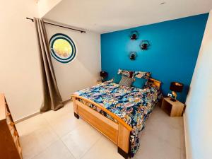 1 dormitorio con 1 cama con pared azul en La Villa Perroquet en Poncins