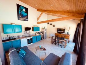 un salon avec un canapé et une cuisine avec des armoires bleues dans l'établissement La Villa Perroquet, à Poncins
