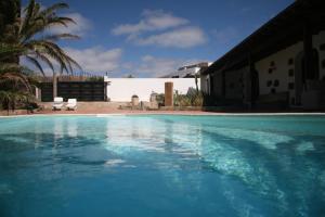 a swimming pool with blue water in front of a house at Casa Palmeral in Mácher