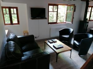 una sala de estar con un sofá de cuero negro y sillas en Chalet Le Tyrolien, au coeur du Boréon, en Saint-Martin-Vésubie