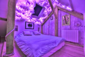 een slaapkamer met een bed in een kamer met paarse verlichting bij ALiCe Au PaYs dEs MerVeiLLeS in Maintenon