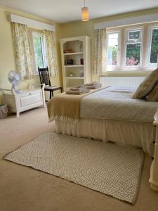 a bedroom with a bed and a chair and windows at Cotswolds Luxury House in Central Bourton Large Sleeps 2-11. Pet Friendly. in Bourton on the Water
