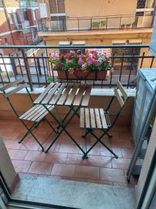 a bench and a table with flowers on a balcony at Minisuite in Rome in Vitinia