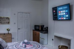 Habitación con cama y TV en la pared. en Bv Comfy Studio At Maningham Lane Bradford en Bradford