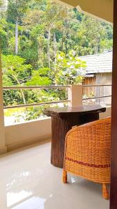 a table and a chair on a balcony with a window at Raja Guest House - Jungle Trekking & Tours Bukit Lawang Sumatra in Bukit Lawang