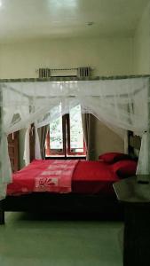 a bedroom with a red bed with a canopy at Raja Guest House - Jungle Trekking & Tours Bukit Lawang Sumatra in Bukit Lawang