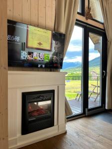 a living room with a fireplace with a flat screen tv at Bramble Tiny House in Zărneşti