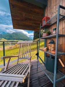 un banco de madera en una terraza con vistas a un campo en Bramble Tiny House, en Zărneşti