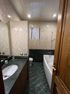 uma casa de banho com um lavatório, uma banheira e um WC. em Guesthouse Parnavaz Mepe em Batumi