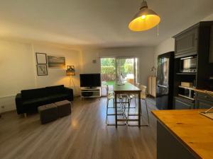 sala de estar con sofá negro y cocina en Splendide appartement de charme avec patio, parking et plage à 3 minutes, en Biarritz
