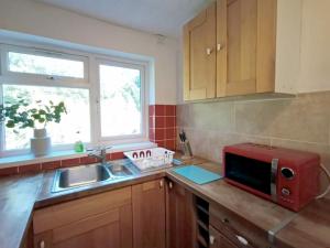 a kitchen with a sink and a microwave on a counter at Cozy 4 Bedroom House in Smethwick with 4 bathrooms perfect for contractors and families in Birmingham