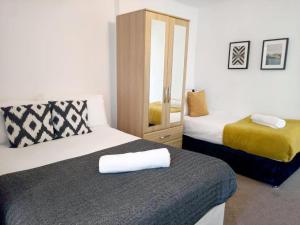 Habitación de hotel con 2 camas y espejo en Cozy 4 Bedroom House in Smethwick with 4 bathrooms perfect for contractors and families en Birmingham