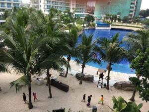 a group of people walking around a pool with palm trees at Azure Condotel in Manila