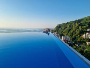 una persona parada en el borde de una piscina con vista al agua en Calypso Kvariati Hotel, en Kvariati