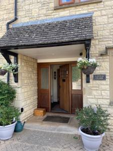 a front door of a house with two potted plants at Cotswolds Luxury House in Central Bourton Large Sleeps 2-11. Pet Friendly. in Bourton on the Water