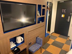 a room with a large flat screen tv and a chair at Henn na Hotel Tokyo Haneda in Tokyo