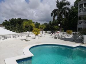 a swimming pool next to a building with a palm tree at Stunning views at sky castles Ocho Rios in Eden Bowers
