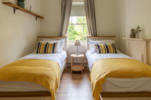 a bedroom with two beds with yellow blankets and a window at Cosy cottage in the heart of Bakewell in Bakewell