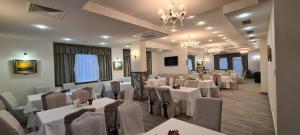 a restaurant with white tables and chairs and a chandelier at ApartHotel Olympus Plaza in Kranevo