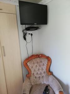 TV de pantalla plana colgada en una pared con silla en Nonesi Lodge, en Queenstown