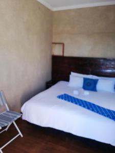 ein Schlafzimmer mit einem weißen Bett und einem Stuhl in der Unterkunft Nonesi Lodge in Queenstown