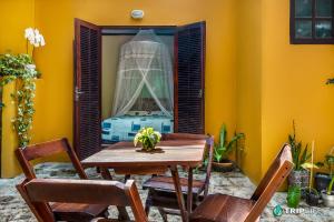 uma mesa e cadeiras num quarto com uma parede amarela em Chalés da Libélula em Ilhabela