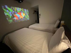 two beds in a room with a painting on the wall at Henn na Hotel Tokyo Haneda in Tokyo